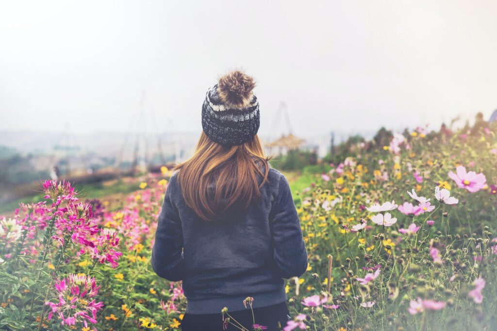 Young woman traveler walking in the flower field